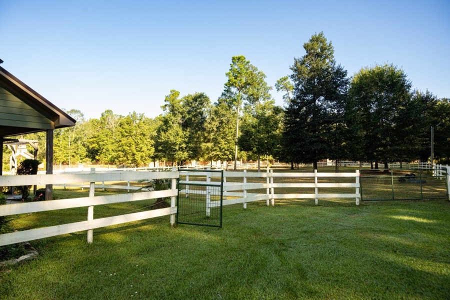 White split-rail fencing and oak canopy at Inspira Ranch — 14-acre private event venue, Livingston TX