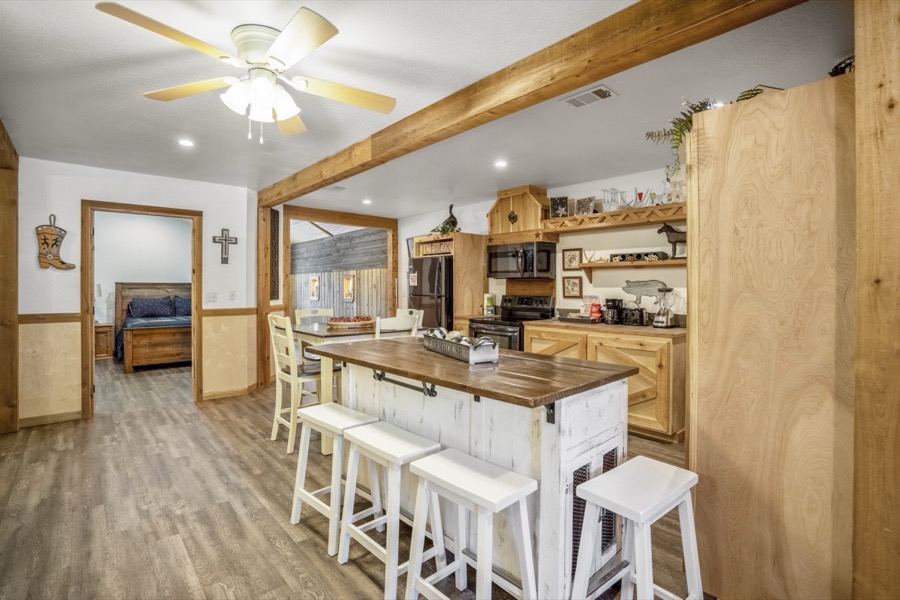 Inspira Ranch apartment open-plan kitchen with white island, bar stools, and wood beam details — Livingston TX