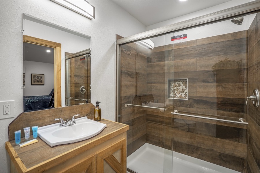 Inspira Ranch apartment private bathroom with glass-enclosed shower and wood-tone vanity — Livingston TX