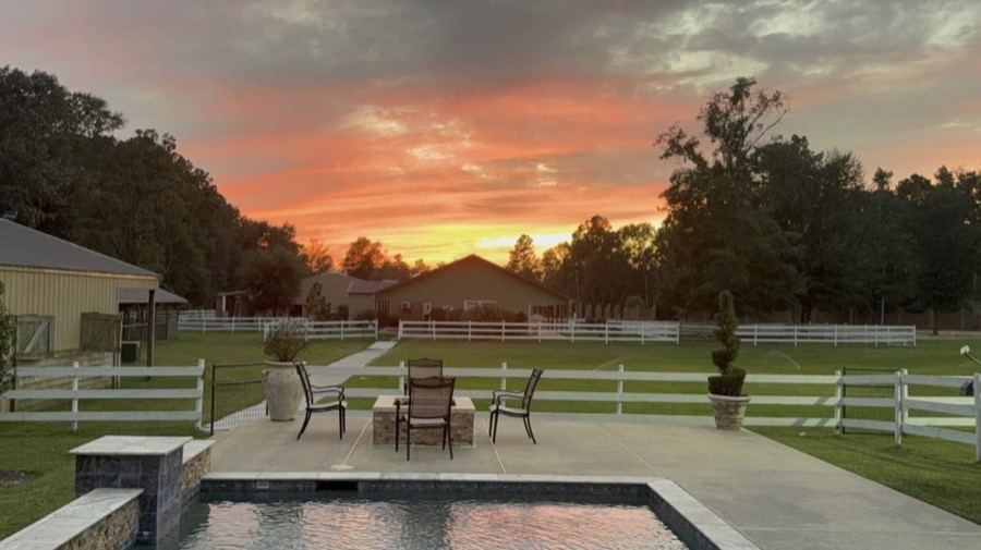 Sunset view over Inspira Ranch pool, fire pit, and event hall on 14 acres