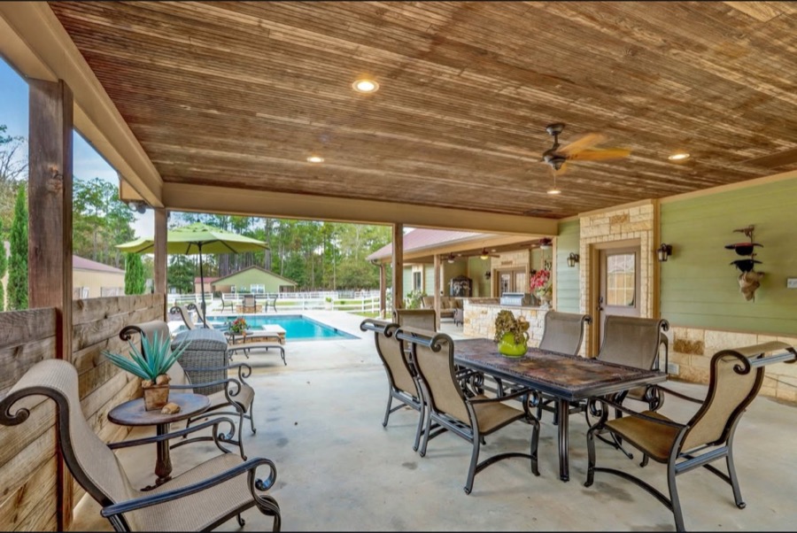Inspira Ranch Casa Principal covered outdoor dining patio with wood-beam ceiling and pool view — Livingston TX