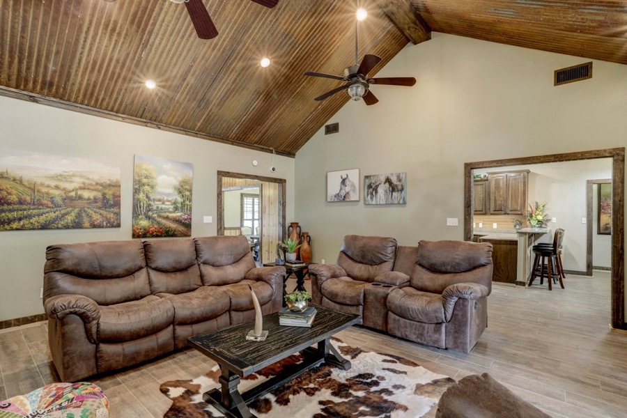 Inspira Ranch living room with vaulted corrugated tin ceiling, leather sofas, and cowhide rug