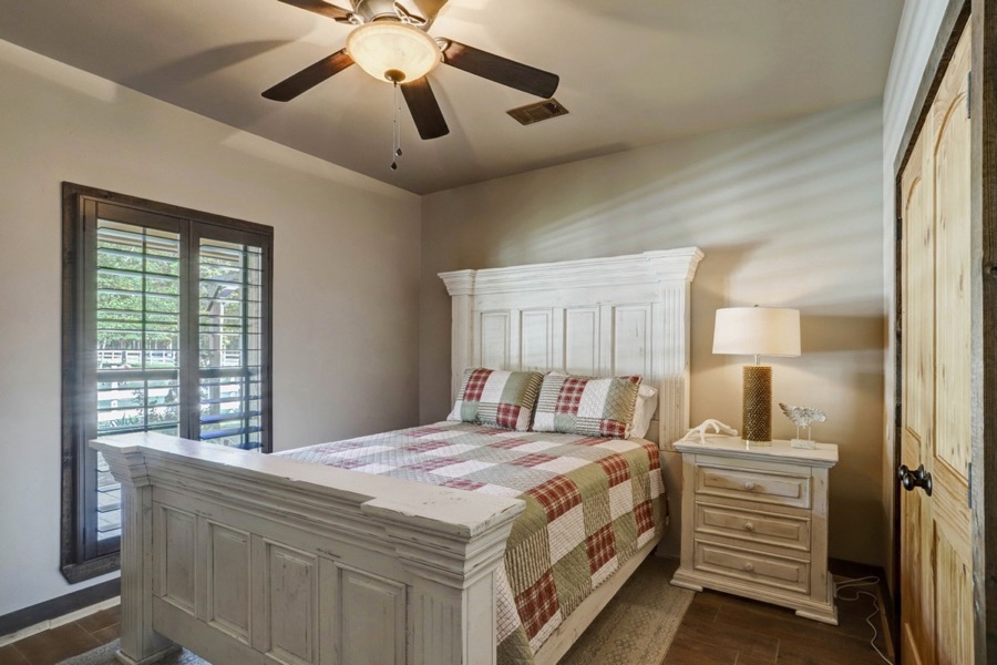 Inspira Ranch bedroom with white painted furniture, plantation shutters, and warm bedside lighting